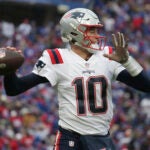 New England Patriots quarterback Mac Jones (10) warms up on the sideline during the first half of an NFL football game against the Buffalo Bills on Sunday, Jan. 8, 2023, in Orchard Park, N.Y.