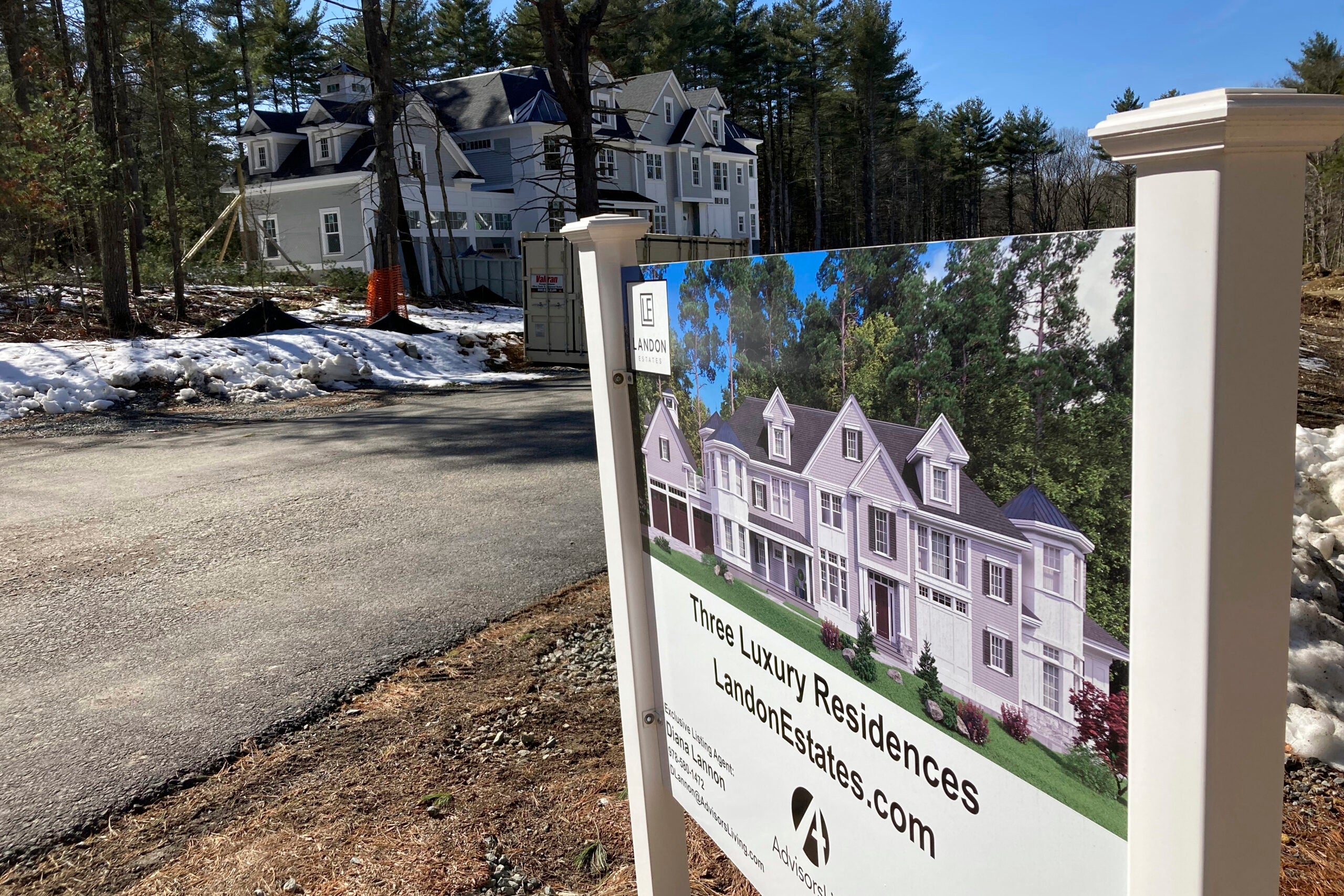 A sign across the street on a dirt lot advertises a mansion for sale to illustrate the weekly mortgage rate announcement.