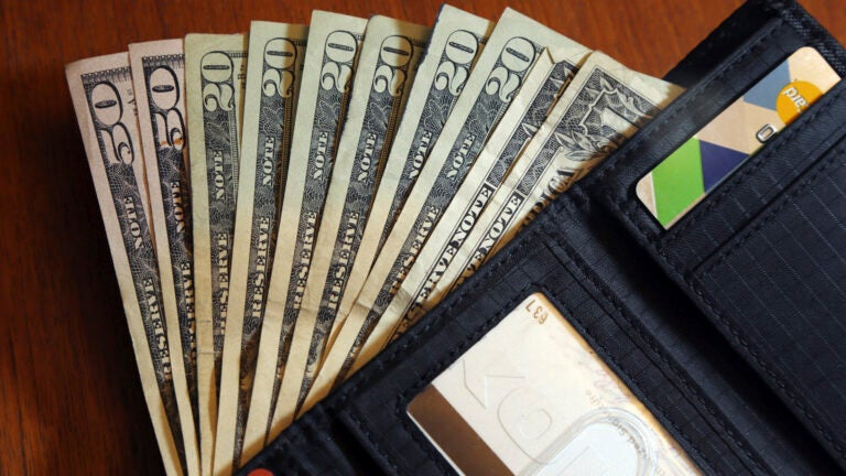 $50, $20, and $1 bills are fanned out from an open black wallet.