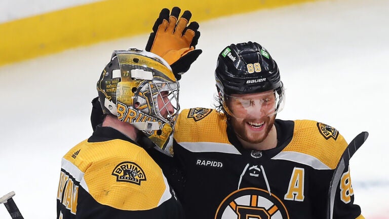Boston Bruins right wing David Pastrnak congratulates Boston Bruins goaltender Jeremy Swayman (1) at the end of the game.