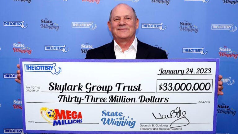 David M. Lipshutz, representing the Skylark Group Trust of Wellesley, stands with a Mega Millions check for $17 million