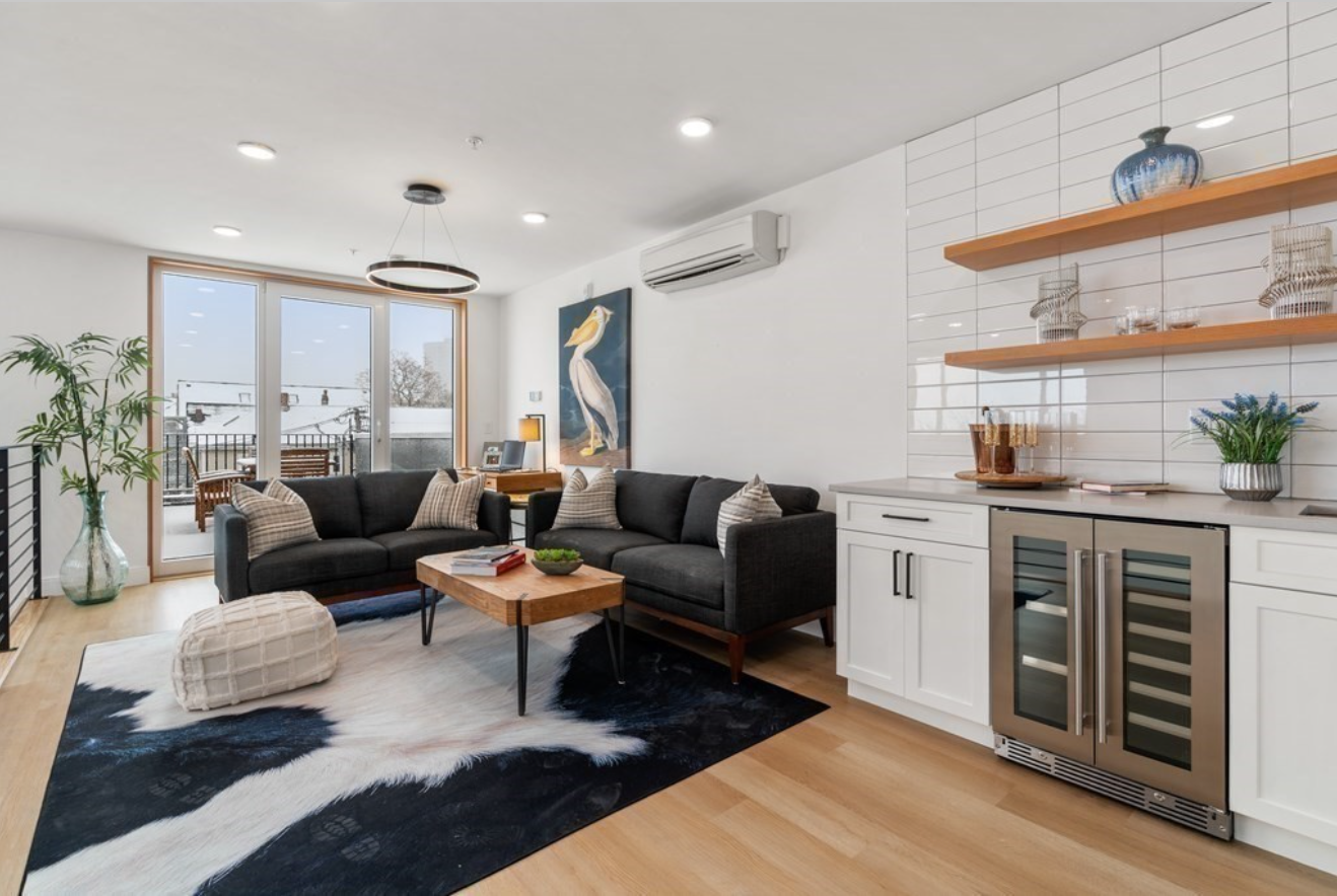The upper level has a wet bar with floating shelves and white stacked subway tile backsplash. Through a sliding glass door is the condo's rooftop deck.