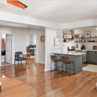 The condo has hardwood floors, white walls, and a breakfast bar with seating for two.