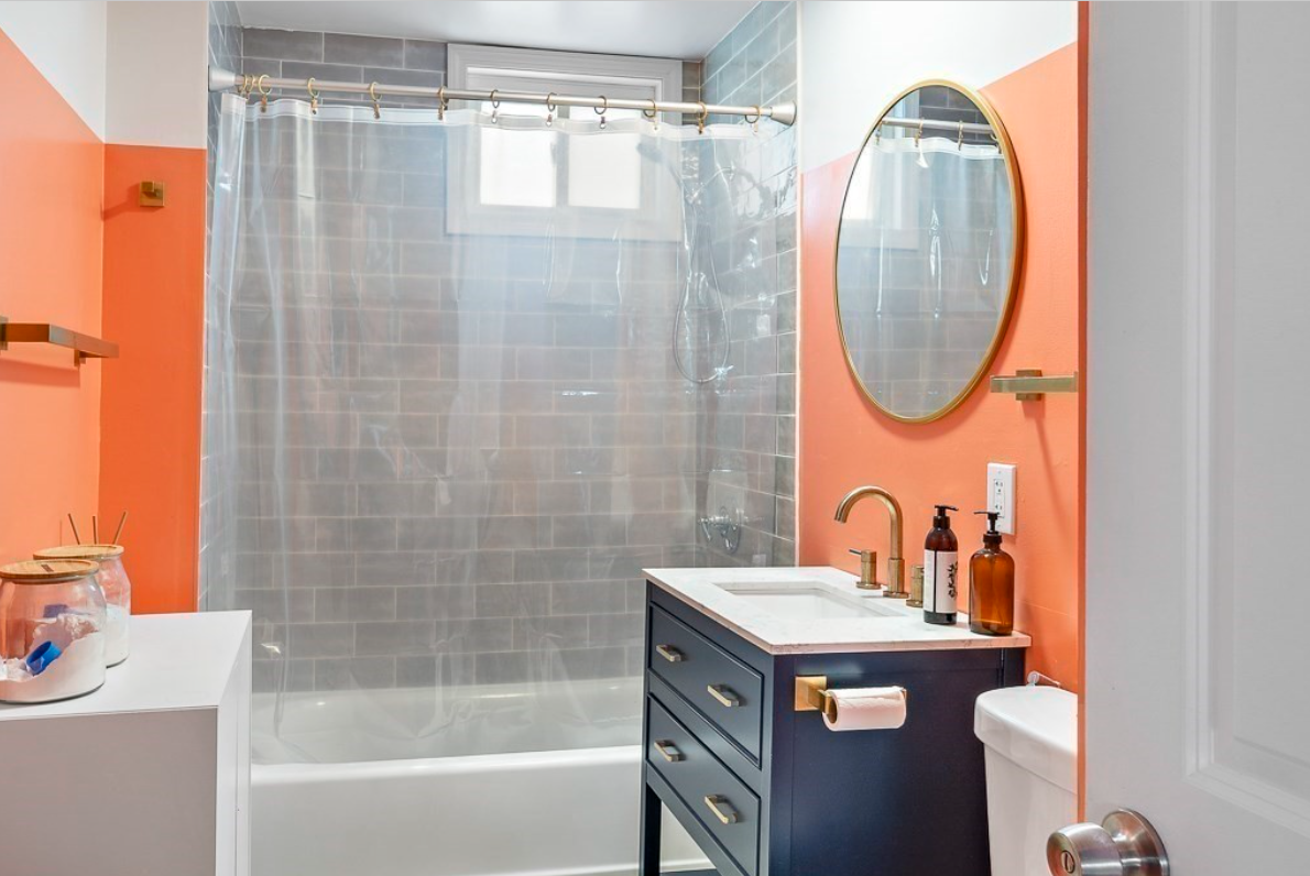 Inside this bathroom is a single vanity with navy blue cabinetry and a combination shower-bathtub with gray tiling.