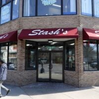Stash's Pizza on Blue Hill Avenue, a tan brick building with a dark red awning and "Stash's" written in white cursive font.