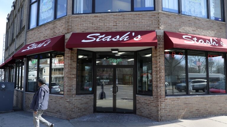 Stash's Pizza on Blue Hill Avenue, a tan brick building with a dark red awning and "Stash's" written in white cursive font.