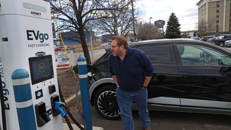 EV owner Nate Sykes looked over a screen to check on his vehicle charging at the new EVgo charger in the parking lot of the Hampton Inn-Boston Logan in Revere.