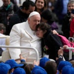 Pope Francis hugs a child .