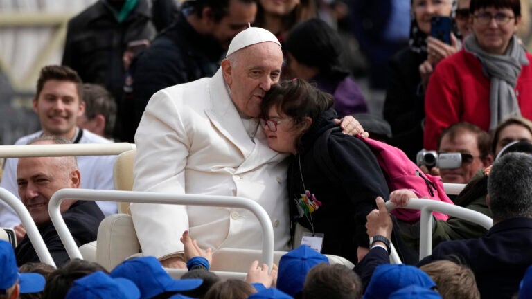 Pope Francis hugs a child .