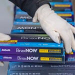 FILE - Youngstown City Health Department worker Faith Terreri grabs two at-home COVID-19 test kits to be handed out during a distribution event, Dec. 30, 2021, in Youngstown, Ohio. The Biden administration on Tuesday quietly launched its website for Americans to request free at-home COVID-19 tests, a day before the site was scheduled to launch.The website, COVIDTests.gov, now includes a link for Americans to an order form run by the U.S. Postal Service where Americans can request four at-home tests per residential address. (AP Photo/David Dermer, File)