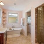 A pink bathroom with a tub and a separate shower, tile flooring, bead board, and speckled shower tile as part of a bold interior design.