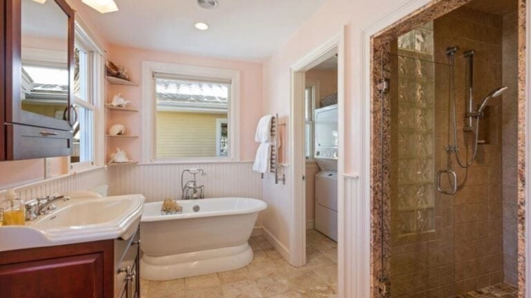A pink bathroom with a tub and a separate shower, tile flooring, bead board, and speckled shower tile as part of a bold interior design.