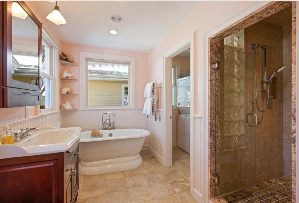 A pink bathroom with a tub and a separate shower, tile flooring, bead board, and speckled shower tile as part of a bold interior design.