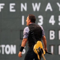 Bruce Springsteen stands in front of the scoreboard at Fenway Park in 2012