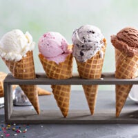 A variety of ice cream scoops in cones with chocolate, vanilla, and strawberry.