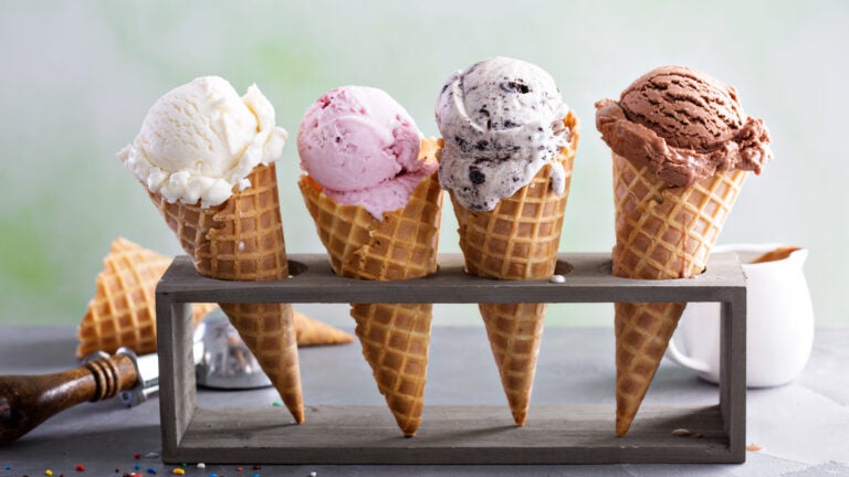 A variety of ice cream scoops in cones with chocolate, vanilla, and strawberry.