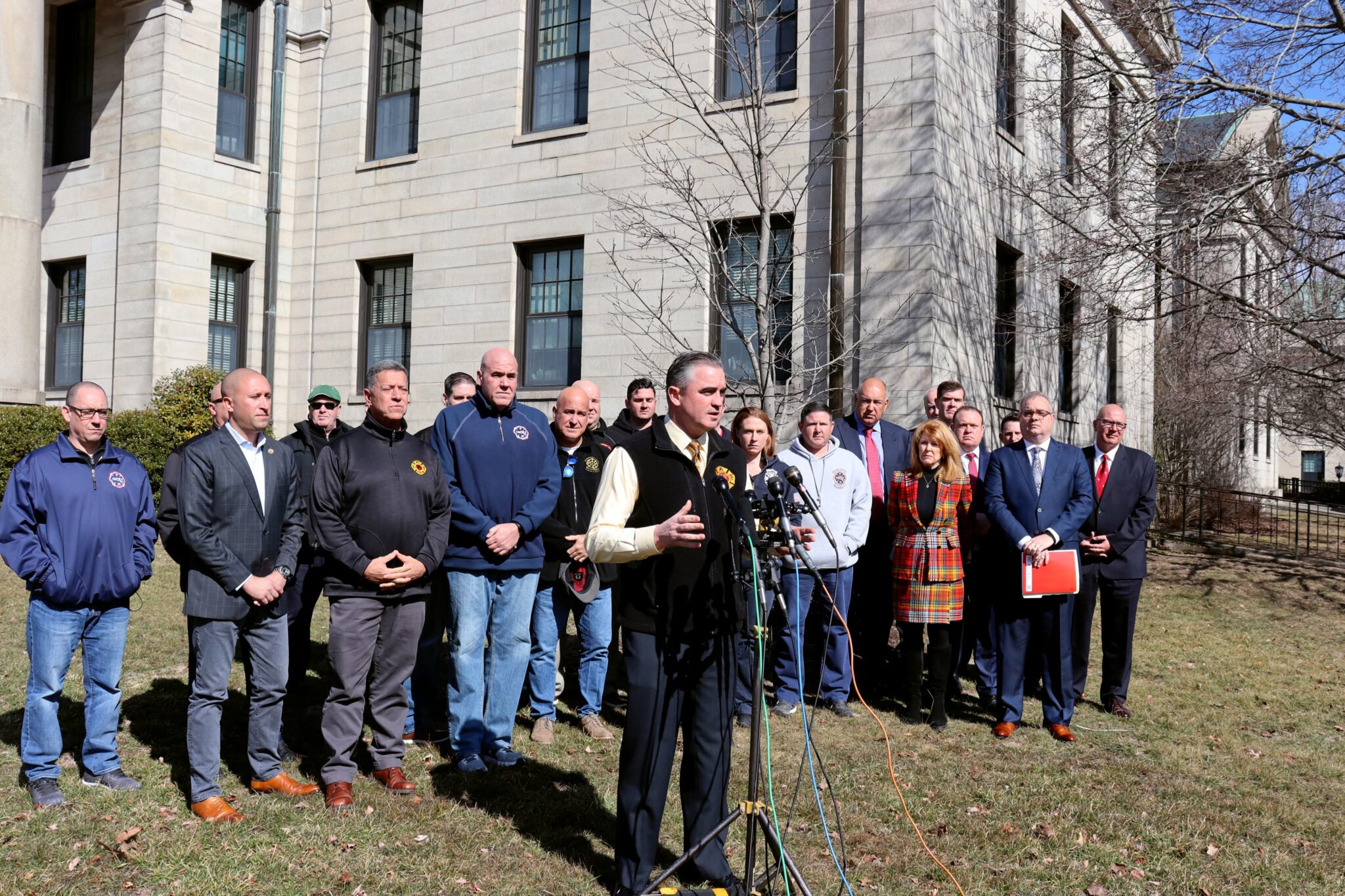 International Association of Firefighters General President, Edward Kelly, stands in front of a group of IAFF representatives in front of a white building