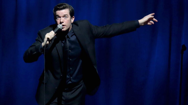 John Mulaney gesticulates while performing comedy.