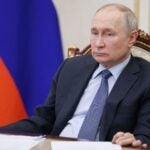 Russian President Vladimir Putin sits at a table, looking forlorn