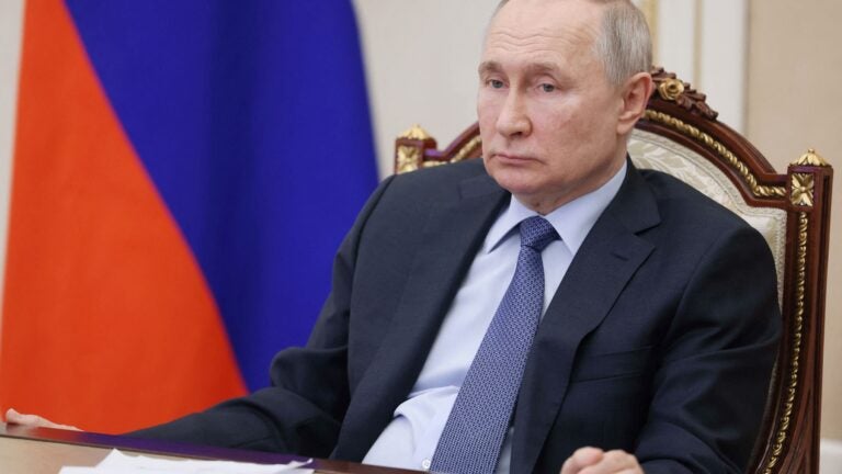 Russian President Vladimir Putin sits at a table, looking forlorn