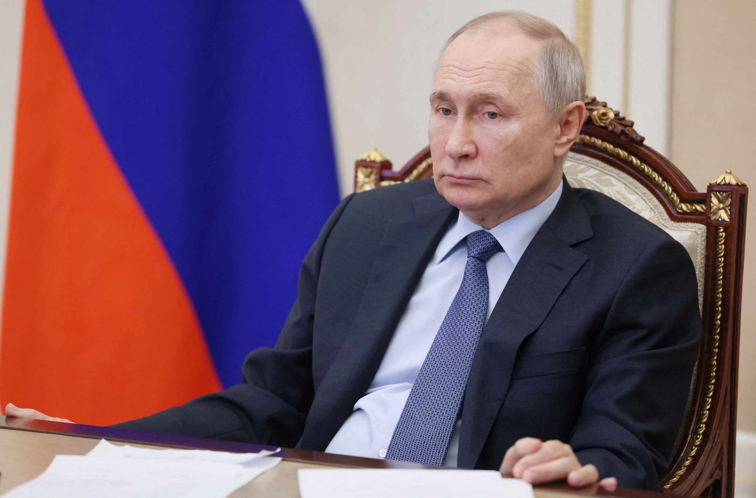 Russian President Vladimir Putin sits at a table, looking forlorn