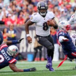 Baltimore Ravens Lamar Jackson splits New England Patriots Ja’Whaun Bentley (8) and Jabrill Peppers (3) during third quarter NFL action at Gillette Stadium.