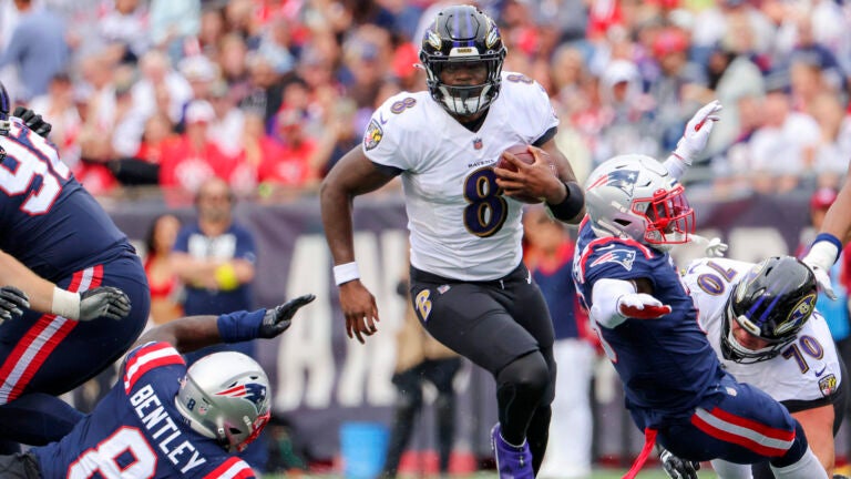 Baltimore Ravens Lamar Jackson splits New England Patriots Ja’Whaun Bentley (8) and Jabrill Peppers (3) during third quarter NFL action at Gillette Stadium.