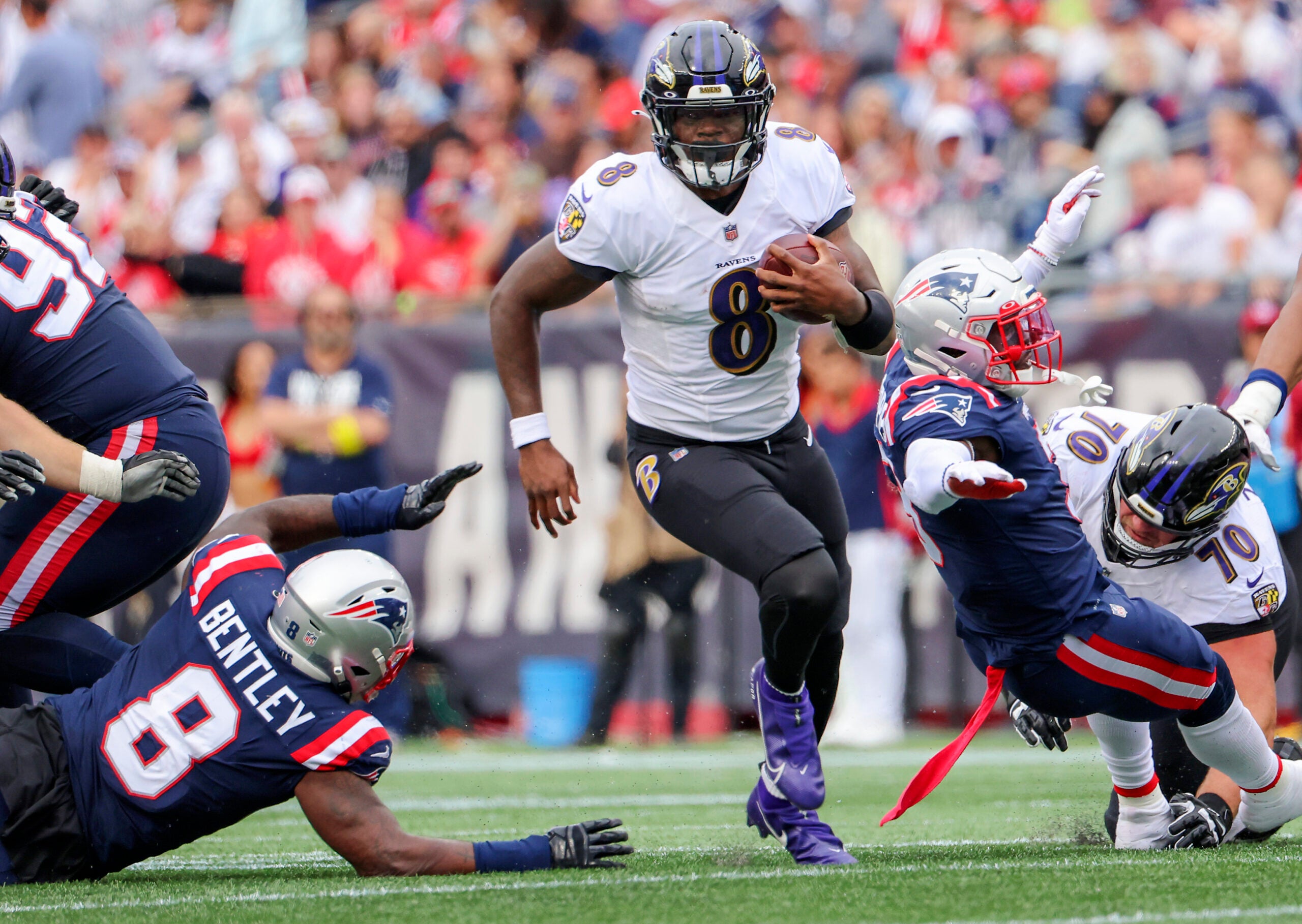 Baltimore Ravens Lamar Jackson splits New England Patriots Ja’Whaun Bentley (8) and Jabrill Peppers (3) during third quarter NFL action at Gillette Stadium.