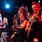 Gail Greenwood and other musicians rock out with guitars and microphones.