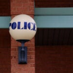 A lamp with the words "POLICE" is attached to the Stoughton Police Department headquarters