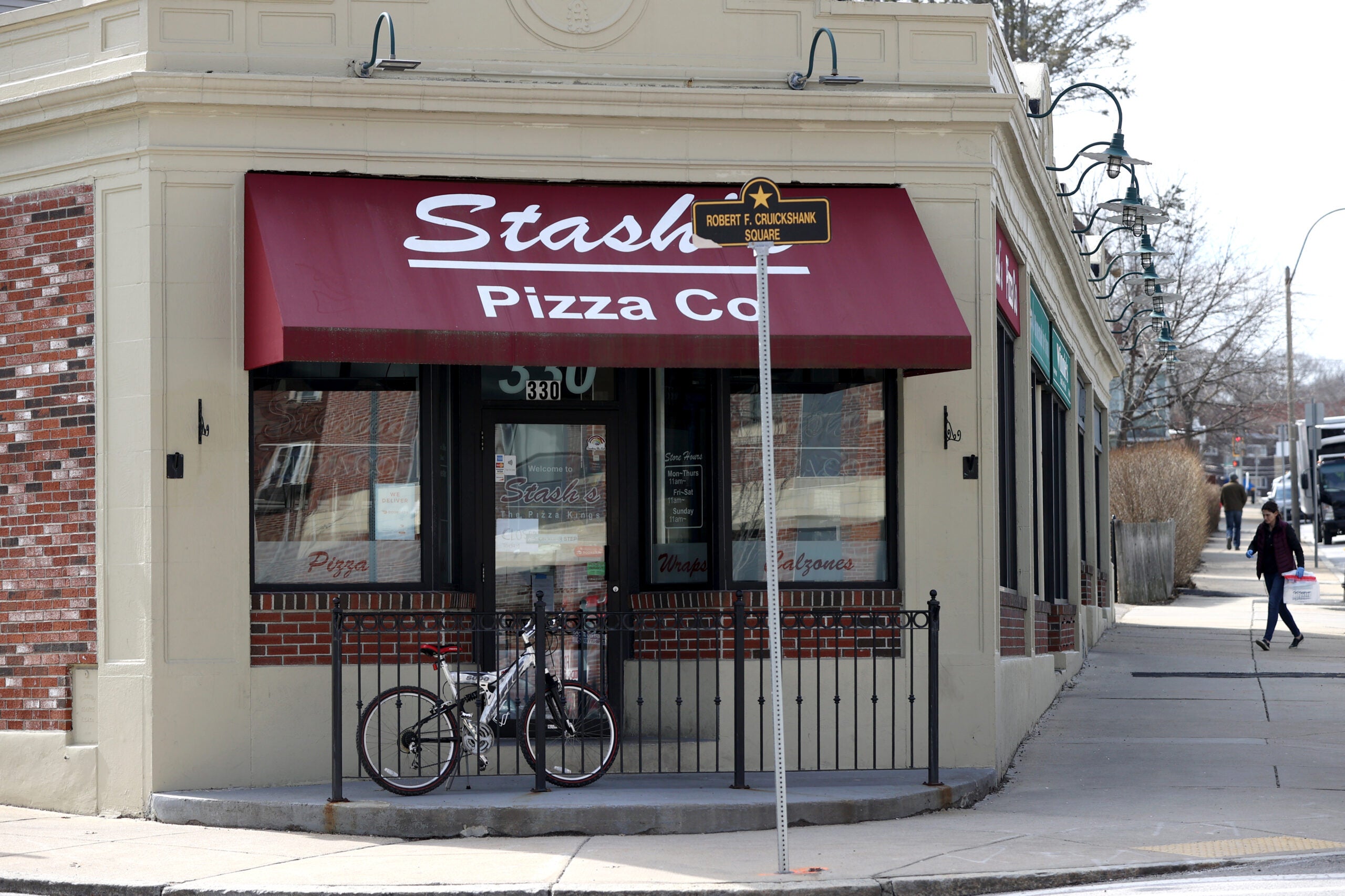 Stash's Pizza in  Roslindale, a tan building with a dark red awning. 