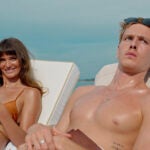 Charlbi Dean Kriek and Harris Dickinson sunbathe in beach chairs in "Triangle of Sadness."