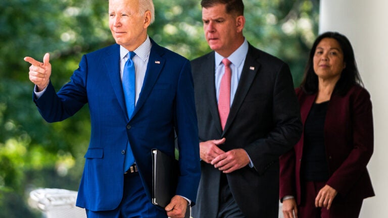 alt = President Biden, in a blue suit with a blue tie, and Labor Secretary Marty Walsh, in a black suit with a pink tie, exit the Oval Office for remarks in the Rose Garden on Sept. 15, 2022.