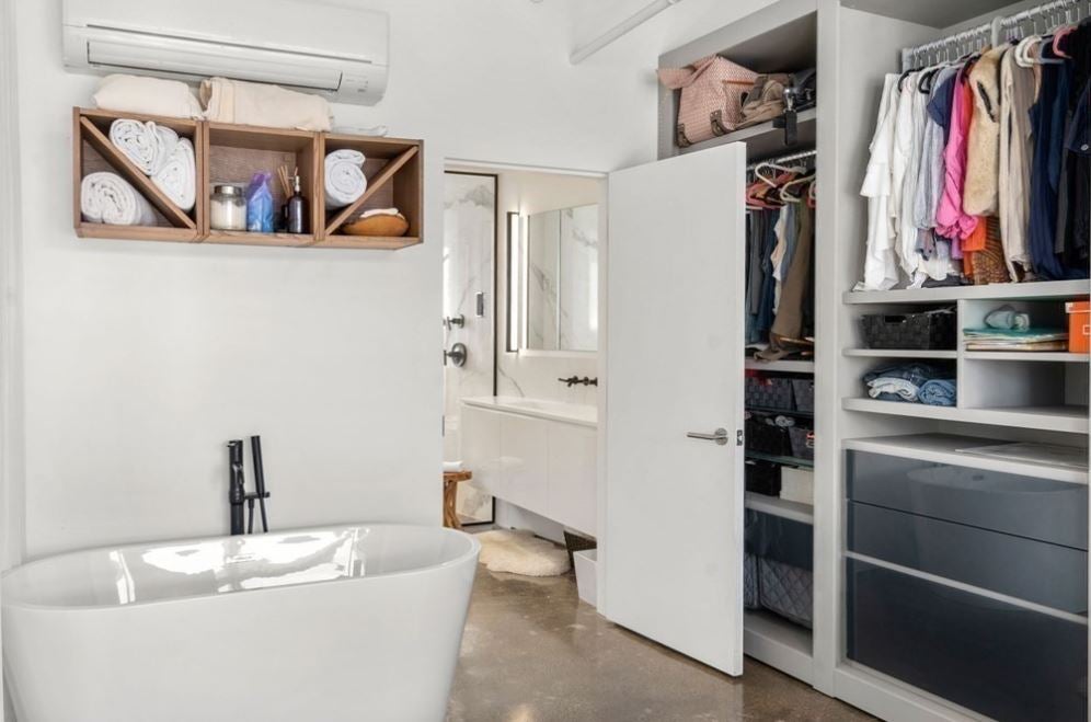 A bathroom with a soaking tub, and storage without doors.