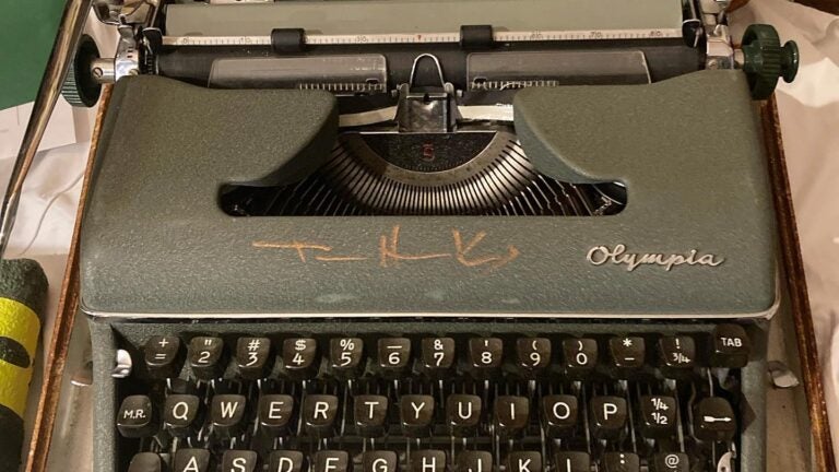 A dark green vintage Olympia typewriter in its wooden carrying case. Tom Hanks has autographed above the keyboard in a bronze marker.