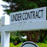 Under contract sign on wooden post. Real estate business.