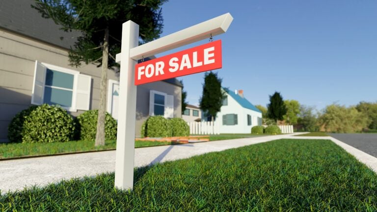 To illustrate the housing market, a real estate sign in front of a house for sale in a nice suburban neighborhood.