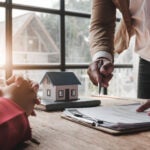 House model with agent and Black home buyer discussing for contract to buy, get insurance or loan real estate or property....