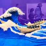 A lego rendition of Hokusai's Great Wave at the MFA is in the foreground and the background is tinted purple.