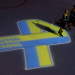Boston Bruins hockey starters, including defenseman Dennis Seidenberg (44), stand next to a ribbon projected onto the ice at TD Garden in Boston, Wednesday, April 17, 2013, during a pregame ceremony in the aftermath of Monday's Boston Marathon bombings.