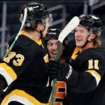 Boston Bruins' Trent Frederic (11) celebrates his goal with Charlie McAvoy (73) and Matt Grzelcyk (48) during the second period of an NHL hockey game, Friday, March 5, 2021, in Boston.