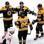 Boston Bruins left wing Brad Marchand, center rear, is congratulated after his goal against the Washington Capitals during the second period of an NHL hockey game Tuesday, April 11, 2023, in Boston. At bottom is Capitals right wing Tom Wilson.