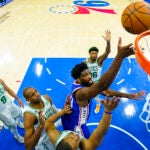 Joel Embiid surrounded by four Celtics players.