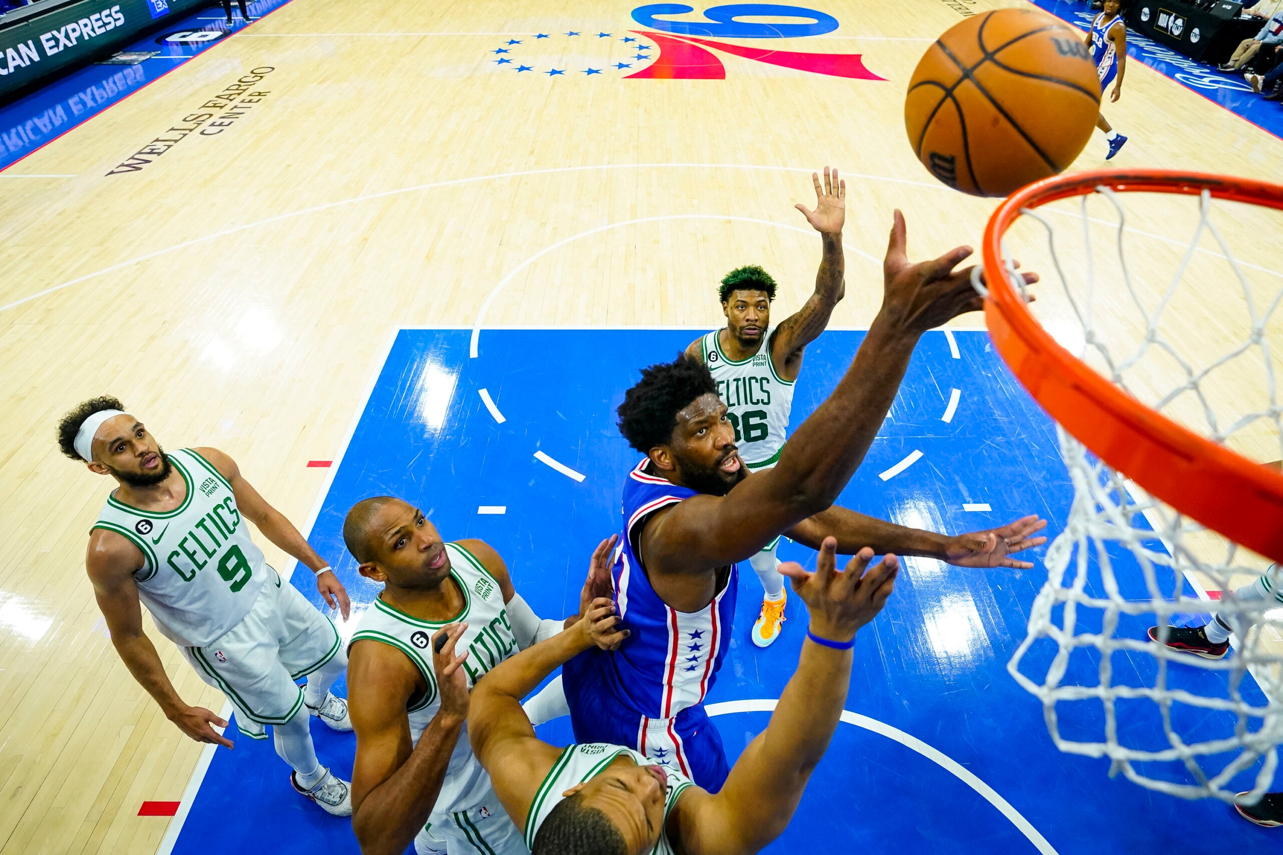 Joel Embiid surrounded by four Celtics players.
