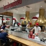 Danilo Gallinari prepares pizza as customers watch.