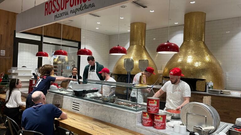 Danilo Gallinari prepares pizza as customers watch.