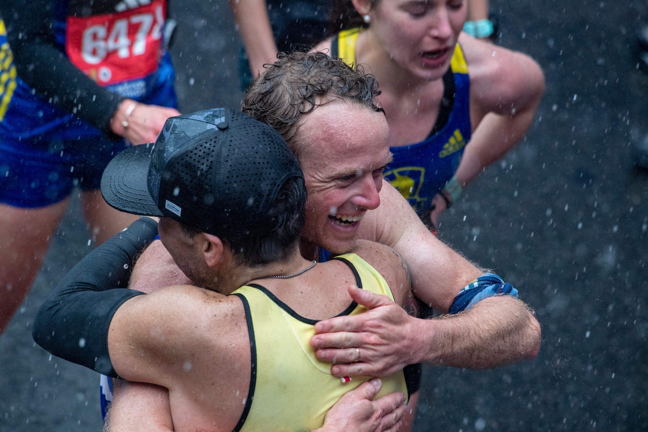 Runners embrace in the rain after finishing the race during the 127th Boston Marathon in Boston, Massachusetts.