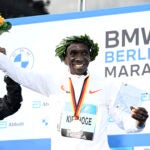 Second placed Kenya's Mark Korir (L) and winner Kenya's Eliud Kipchoge celebrate on the podium after the Berlin Marathon race on September 25, 2022 in Berlin. - Kipchoge has beaten his own world record by 30 seconds, running 2:01:09 at the Berlin Marathon.
