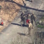 Jack Teixeira, in T-shirt and shorts, being taken into custody Thursday, in Dighton.