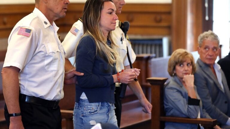 Karen A. Read, 42, girlfriend of the late Boston Police Officer John O’Keefe, is led into court in handcuffs for her arraignment in Norfolk Superior Court on charges of second-degree murder in O’Keefe’s death.